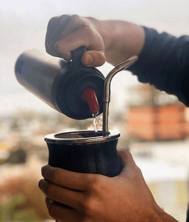hombre cebando mate con termo con media manija y pico cebador